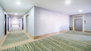 A long, narrow hallway with carpeted floors and doors on both sides leading to elevators. - Greentree Inn Shandong Linyi Yishui County Angel G (Linyi)