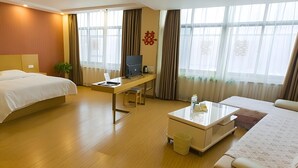A hotel room with a bed, desk, chair, and a small coffee table. - Greentree Inn Shandong Linyi Yishui County Angel G (Linyi)