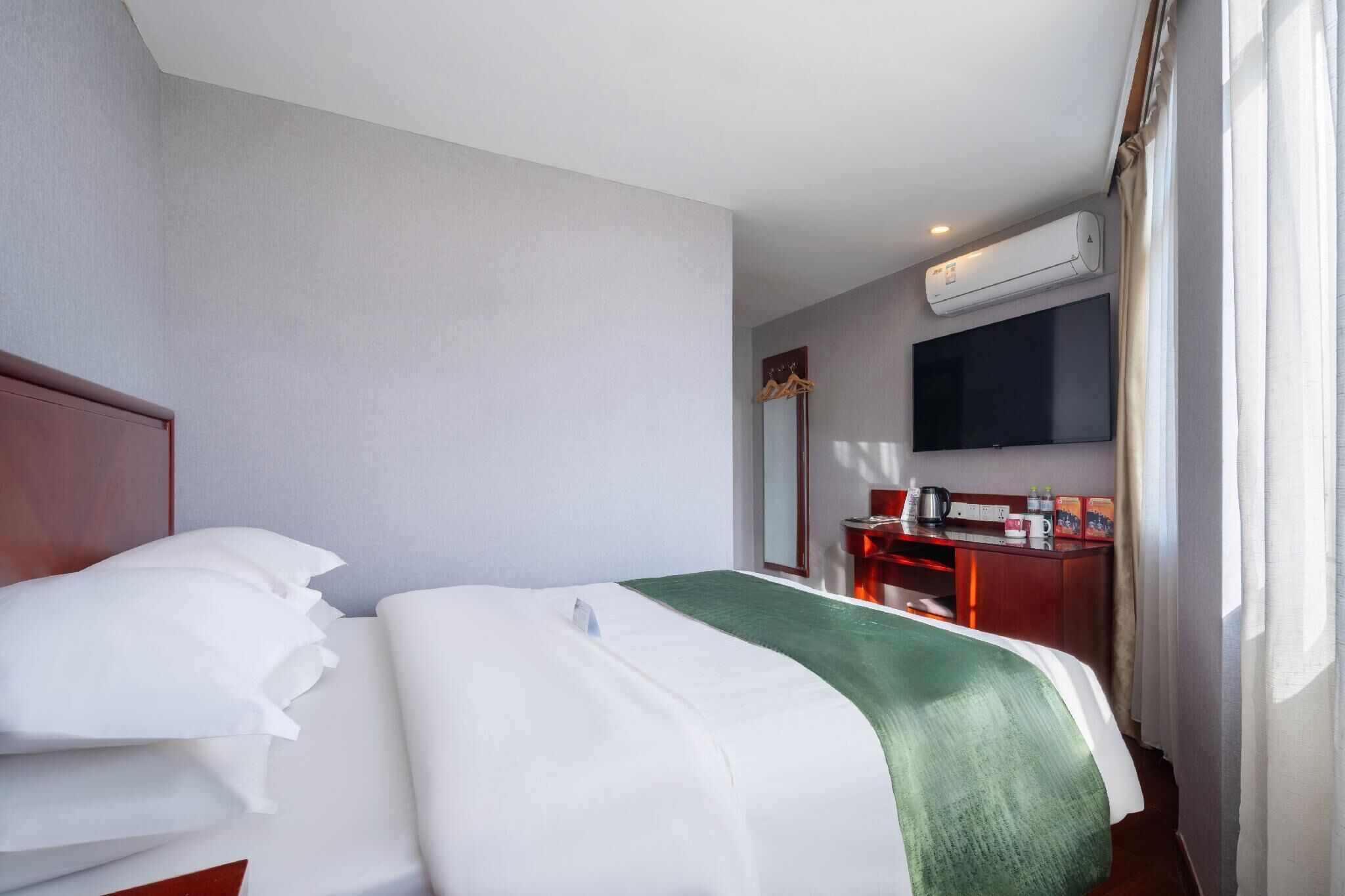 Una habitación de hotel con cama, escritorio, televisor y aire acondicionado.