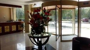 A lobby with a reception desk, a glass table with flowers, and a revolving door. - Greentree Inn Shandong Linyi Yishui County Angel G (Linyi)