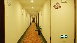 A hotel hallway with a carpeted floor, framed pictures on the walls, and an emergency exit sign. - Greentree Inn Shandong Linyi Yishui County Angel G (Linyi)