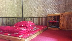 A room with a wooden bed, a red carpet, and a woven wall. - OYO 2922 Wisma Kampoeng Ciherang Syariah (Sumedang)