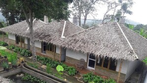 A traditional thatched-roof house with a small garden and a water feature. - OYO 2922 Wisma Kampoeng Ciherang Syariah (Sumedang)