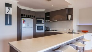 Una cocina moderna con una isla central, horno empotrado, microondas y refrigerador.