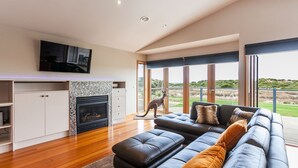 Una sala de estar moderna con chimenea, un sofá grande y un televisor montado en la pared.