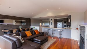 Una sala moderna con un sofá modular, un comedor y una cocina con barra.
