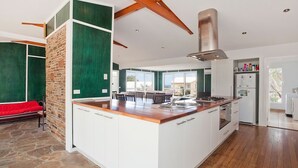 Eine moderne Küche mit einer zentralen Kochinsel, weißen Schränken und einer Wand in Steinoptik.