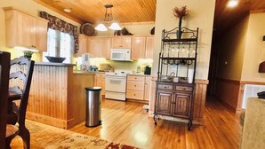 A spacious kitchen with wooden cabinets, a central island, and a dining area with a chair.