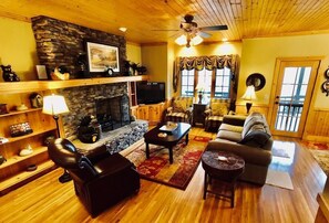 Relax in this inviting living room with a fireplace, sofas, coffee table, and television.