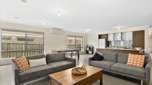 A modern apartment with two grey sofas, a wooden coffee table, and a kitchen in the background. - Ocean View Crescent 59 Torquay Pet Friendly (TORQUAY)