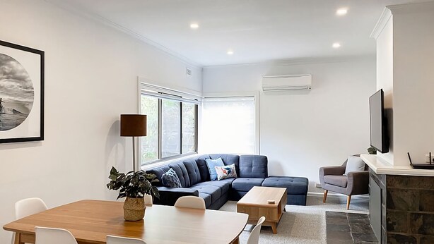 A modern living room with a sofa, a dining table, and a TV. - Immaculately prepared property is only 40 metres from the foreshore (TORQUAY)