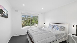 A bedroom with a large bed, a window with a view of greenery, and a painting on the wall. - Puebla Casa 17  Walk to Beach & Shops (TORQUAY)