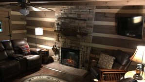 Un salon chaleureux avec une cheminée en pierre, des canapés en cuir et un plancher en bois.