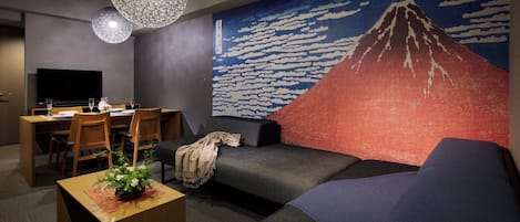 Moderni hotellihuone, jonka seinällä on suuri Fuji-vuorta esittävä seinämaalaus. Huoneessa on myös sohva, koristekasvi, sohvapöytä, työpöytä, jossa on litteänäyttöinen televisio, sekä kaksi riippuvalaisinta, jotka ovat pyöreän muotoisia.