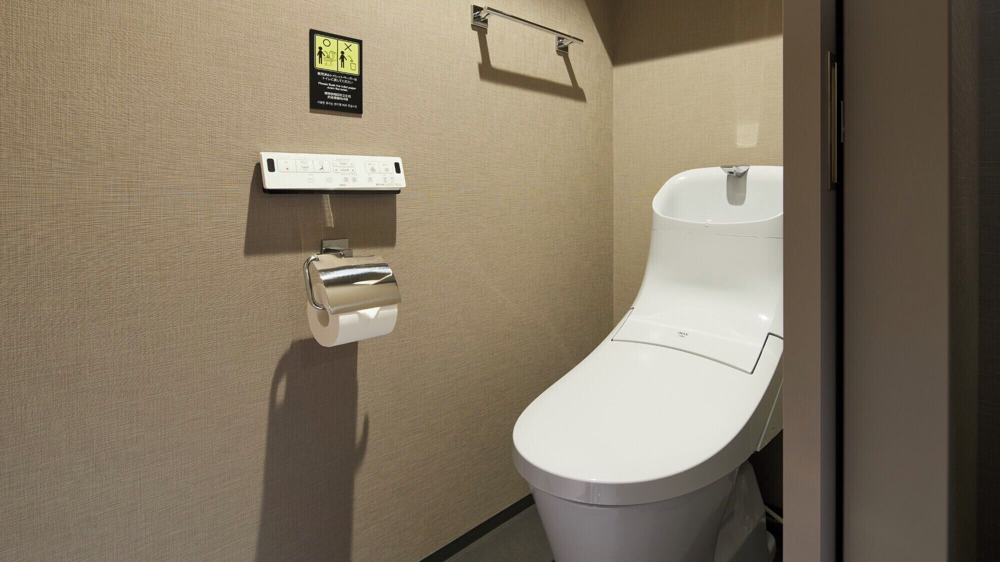 Un bagno moderno con un water bianco, un asciugamani ad aria e un dispenser di carta.
