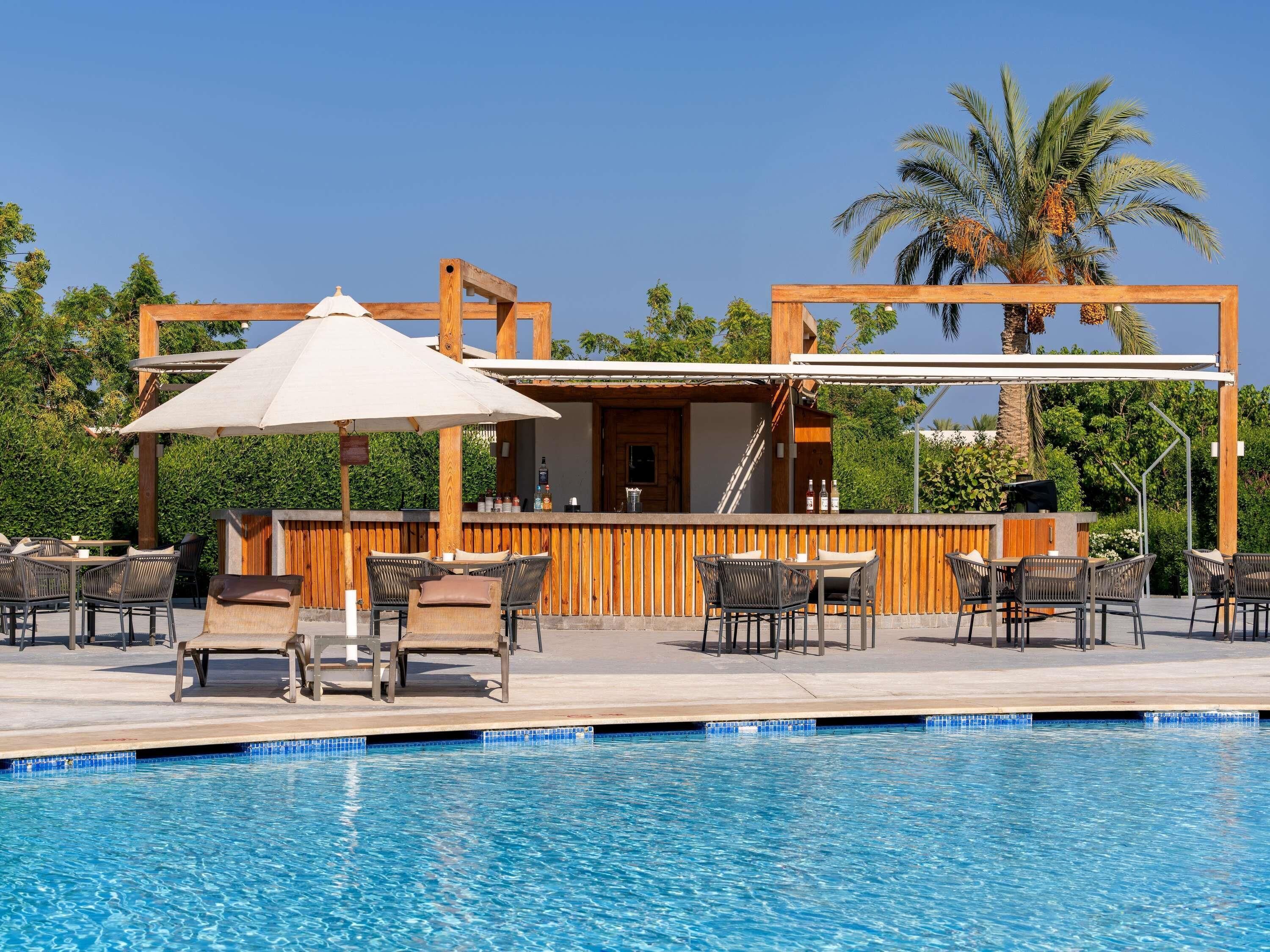 A poolside area with outdoor seating, a bar, and a wooden pergola.