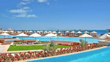 A resort with multiple swimming pools, lounge areas, and a view of the sea.