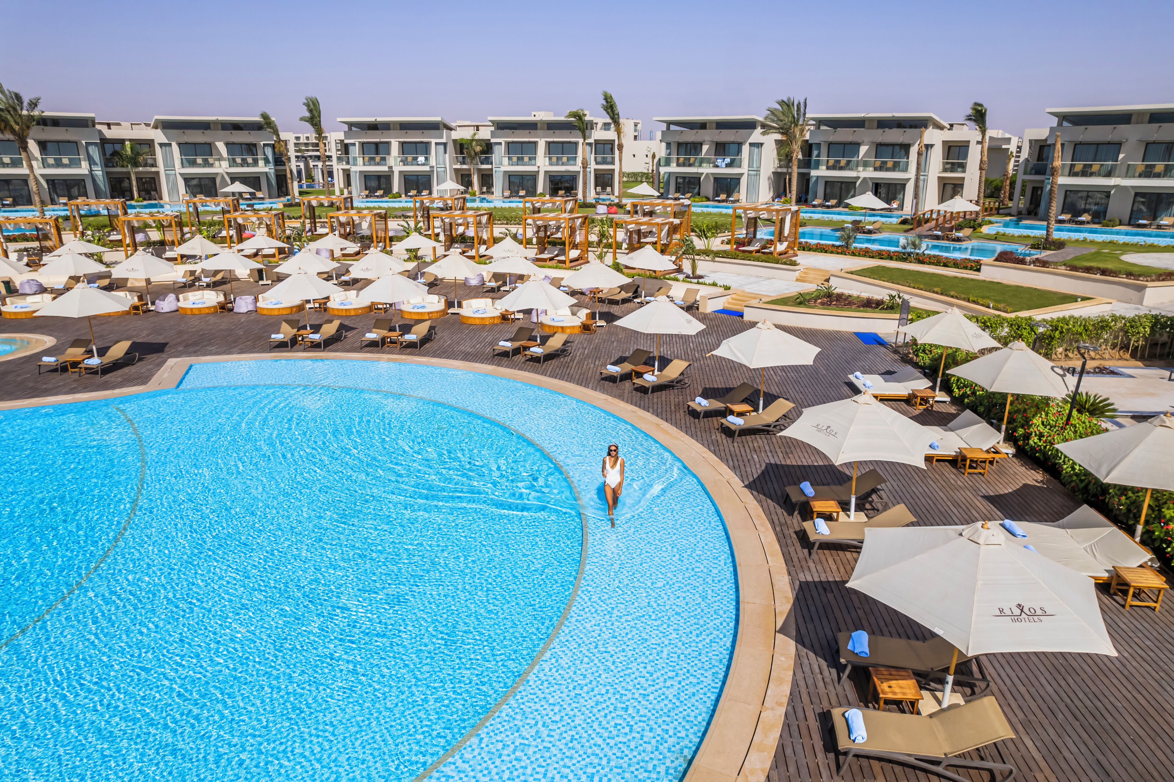 Un complexe hôtelier doté de plusieurs piscines, de chaises longues et de parasols.