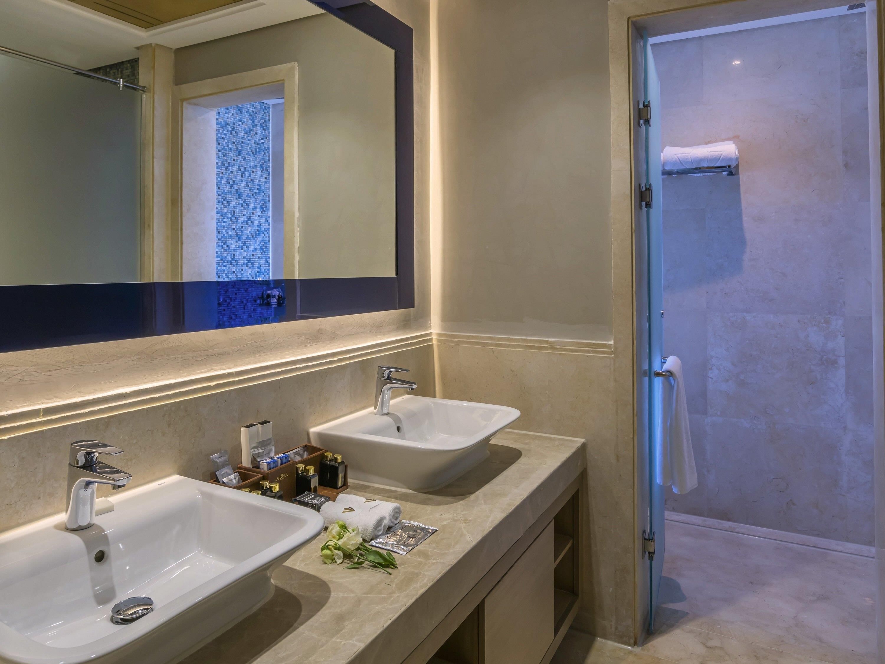 A bathroom with two sinks, a mirror, a shower, and a towel rack.
