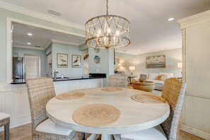 Enjoy meals in this stylish dining area with a round table and four chairs, surrounded by a chandelier and a modern kitchen.