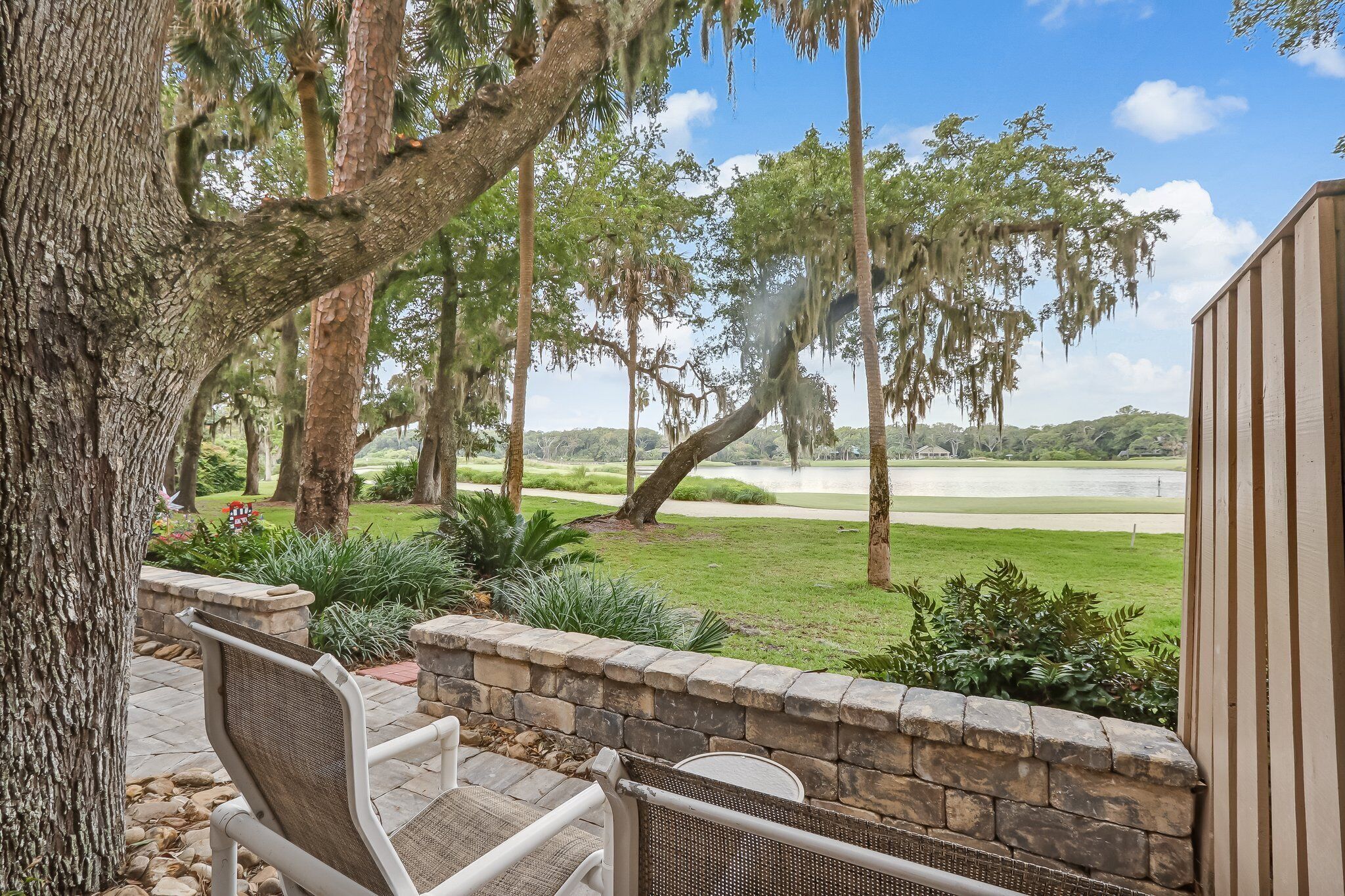 A patio with stone walls and a view of a golf course.