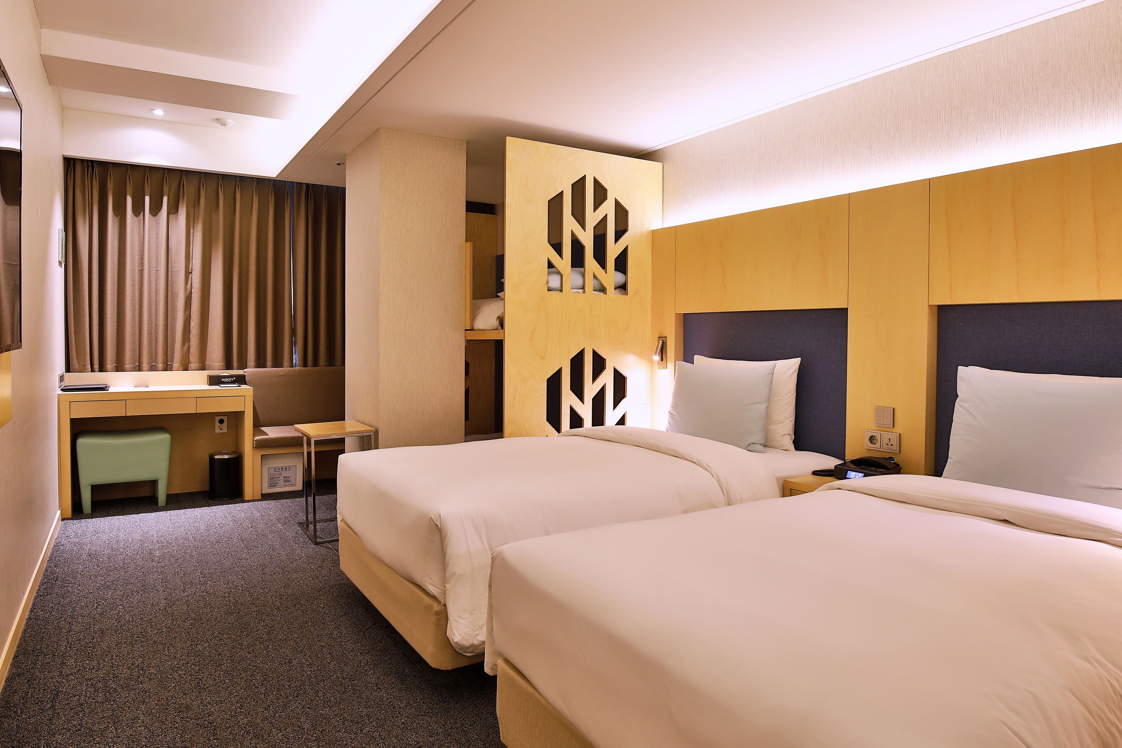 A hotel room with two beds, a desk, and a wardrobe.