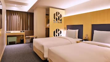 A hotel room with two beds, a desk, and a wardrobe.