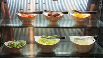 A buffet with various bowls of food, including salads and fruits, arranged on shelves.