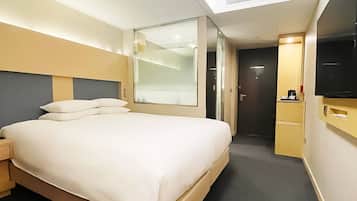 A hotel room with a bed, a TV, a desk, and a door.