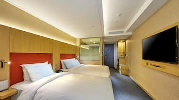 Quarto de hotel com duas camas, uma televisão grande e um espelho.