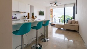 Et moderne køkken med barområde, stort vindue med udsigt og sofa i opholdsstuen.