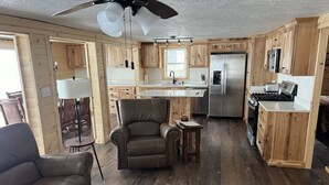 Une cuisine spacieuse dotée de meubles en bois, d’un réfrigérateur en acier inoxydable, d’une cuisinière et d’un coin repas comprenant un canapé en cuir et une petite table.