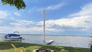 Un espace herbeux avec un foyer et deux chaises Adirondack jaunes, disposées face à un lac.