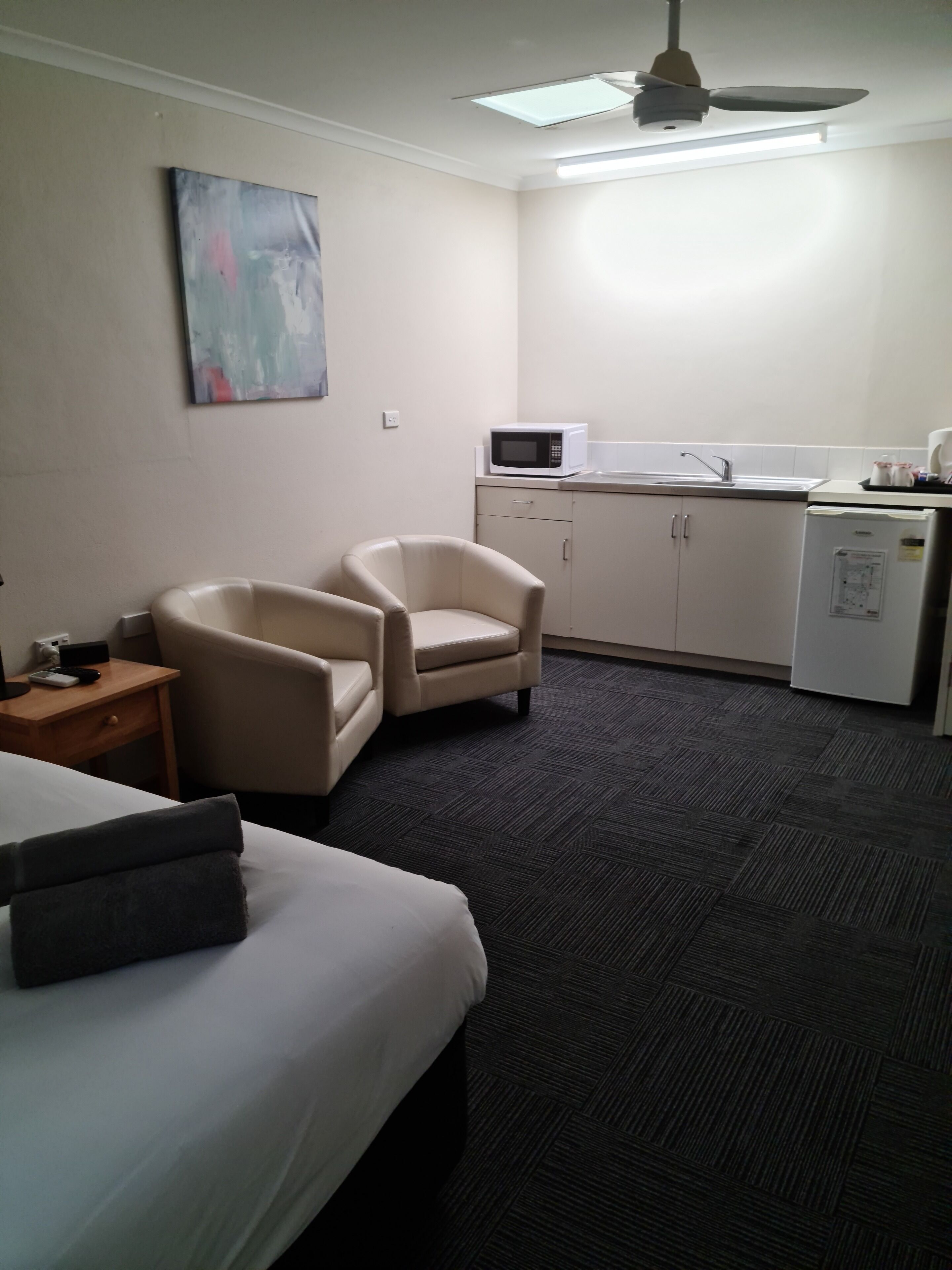 Une chambre d’hôtel équipée d’un lit, d’une chaise, d’un bureau, d’un four à micro-ondes, d’un réfrigérateur et d’un ventilateur de plafond.