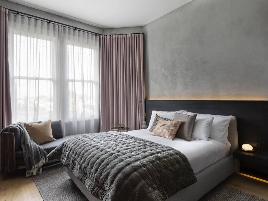 Quarto moderno com uma cama grande, uma mesa de cabeceira e um criado-mudo.