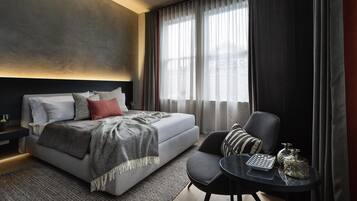 A modern bedroom with a bed, a chair, a small table, and a window with curtains.