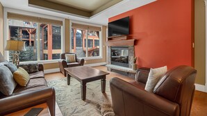 A modern living room with a fireplace, leather furniture, and large windows offering a view of the outside. -  Mountain Luxury Resort (Canmore)
