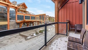 A balcony with a view of a building with large windows and a wooden structure. -  Mountain Luxury Resort (Canmore)