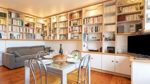 Una sala de estar acogedora con comedor, rodeada de estanterías llenas de libros.