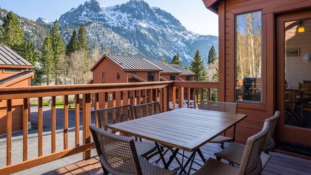 A wooden deck with a table and chairs, overlooking a mountain range. - Aspen Meadows #2 Sun-Filled, 3 bedroom condo (June Lake)