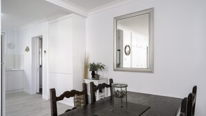 A dining area with a dark wooden table, white cabinets, and a mirror on the wall. - Nobby's 9 - Amazing Ocean Views (Port Macquarie)