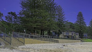 A beach with a staircase leading to a building with a blue roof. - Nobby's 9 - Amazing Ocean Views (Port Macquarie)