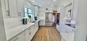 A modern kitchen with white cabinetry, stainless steel appliances, and a wooden floor.