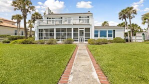 A two-story building with a balcony, surrounded by well-maintained lawns and palm trees.