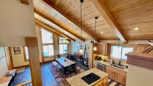 Una cocina amplia con armarios de madera, encimera de granito y una isla central con estufa. Hay ventanas grandes que ofrecen luz natural y vistas al exterior.