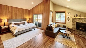 Un dormitorio con una cama grande, un sofá, una chimenea y vistas al exterior.