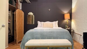 A bedroom with a bed, a bench, a wardrobe, a mirror, and a lamp.