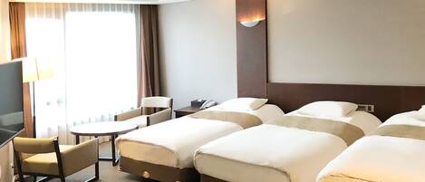 Une chambre d’hôtel avec un grand lit, un bureau, une chaise, une télévision et une fenêtre avec des rideaux.