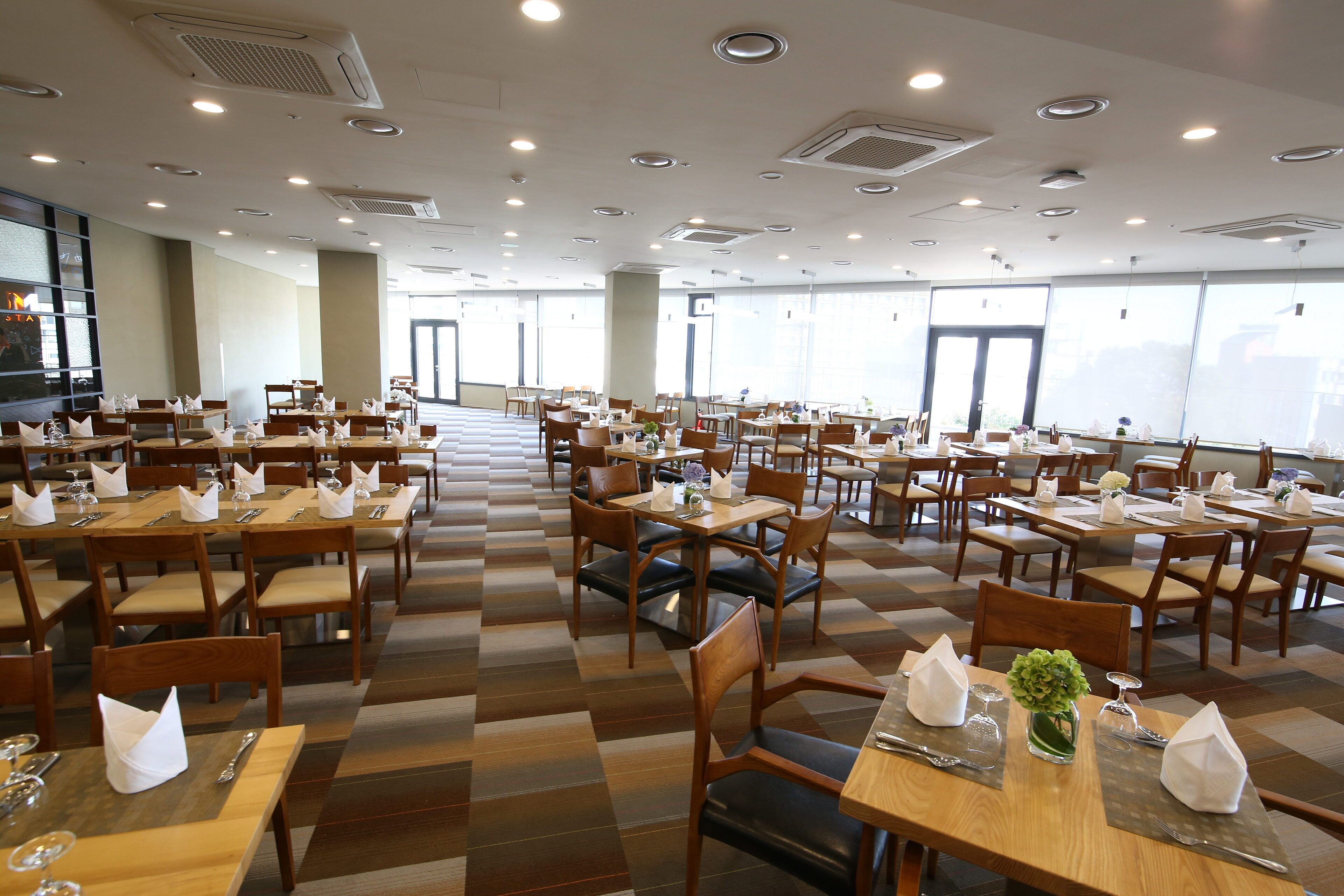 A spacious dining area with multiple tables and chairs, arranged in a grid pattern.