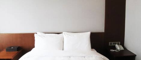 Habitación de hotel con una cama bien hecha, una mesita de noche con teléfono y una lámpara de pared.